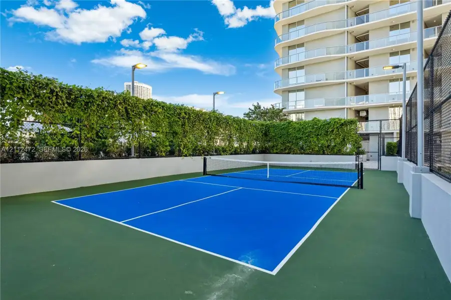 Pickleball court featuring a dual-tone surface, perimeter fencing, and integrated lighting