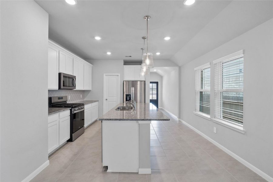 The extended granite countertop creates a convenient breakfast bar, providing a casual and inviting space where stools can be added for quick meals or long conversations.