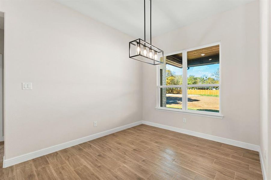 Unfurnished dining area featuring wood tiled floors and a chandelier