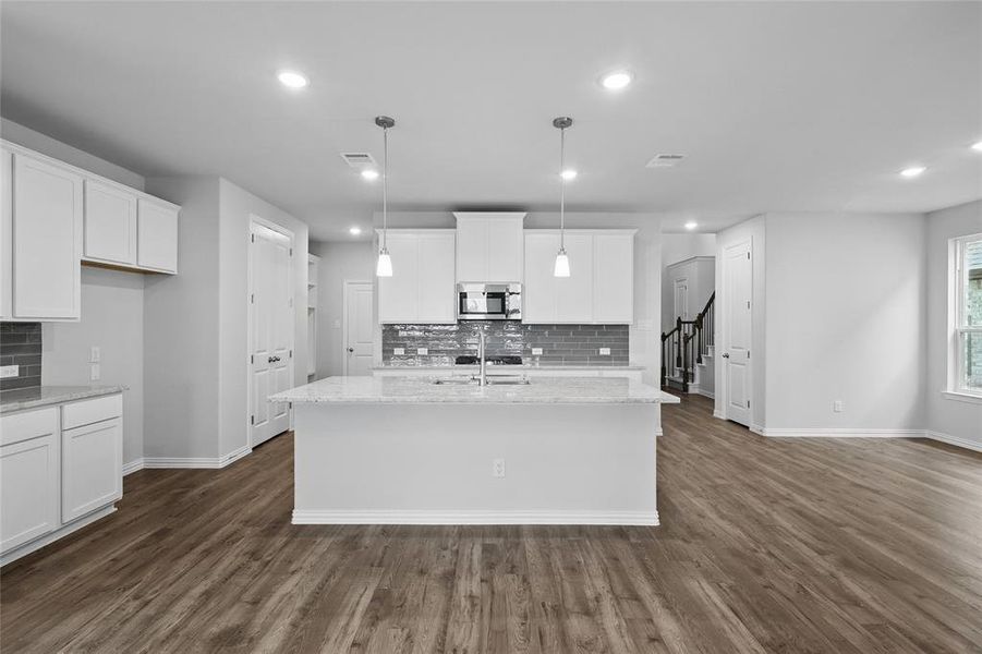 Kitchen featuring tasteful backsplash, decorative light fixtures, light stone counters, white cabinetry, and recessed lighting