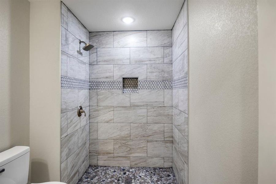 Bathroom with a shower stall and a textured wall Bathroom with a shower stall and a textured wall