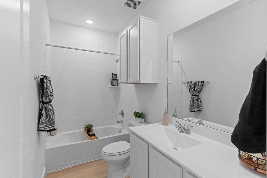 The secondary bathroom is both practical and beautiful, featuring a fresh white vanity, modern fixtures, and a tub-and-shower combo with chic tile surroundings—perfect for guests or family mornings. Every detail is designed with comfort and style in mind!