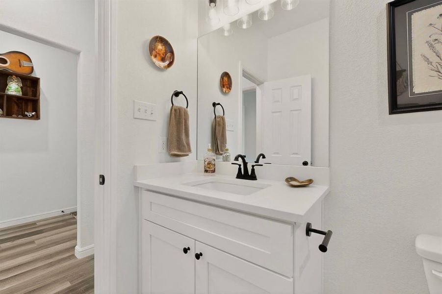 Bathroom featuring a white vanity with shaker-style cabinetry, a white countertop, and an integrated sink with a matte black faucet