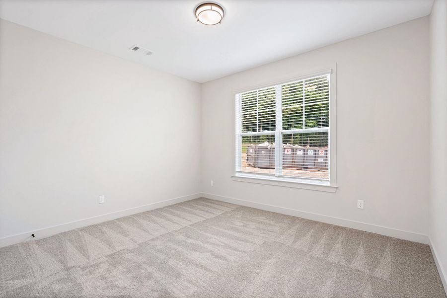 Spacious room featuring neutral carpeting, light-colored walls, and a large window with white blinds Spacious room featuring neutral carpeting, light-colored walls, and a large window with white blinds