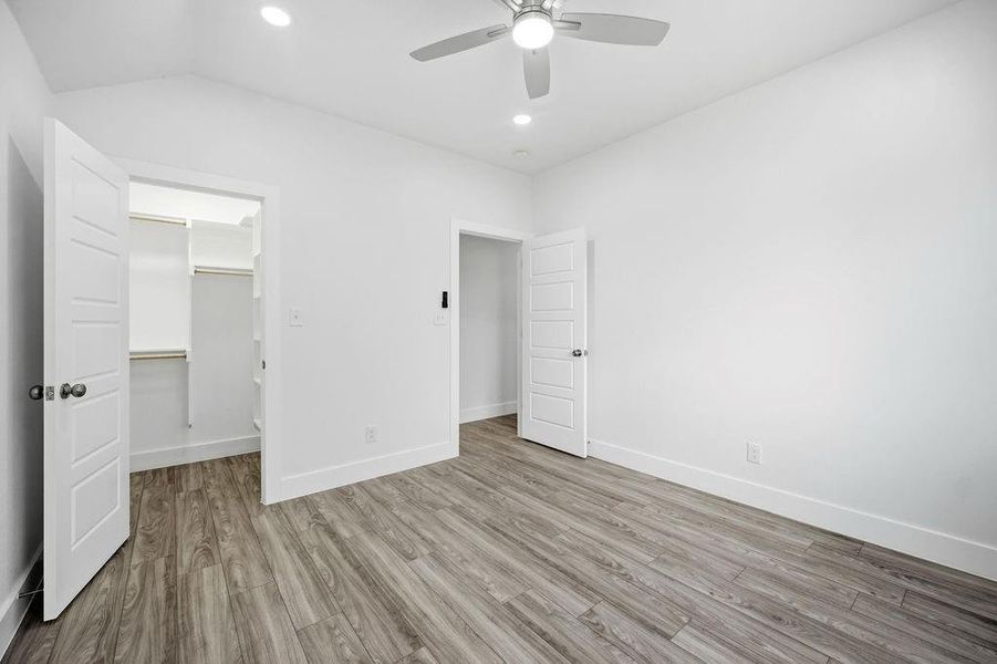Spacious room with wood-finish flooring and a vaulted ceiling Spacious room with wood-finish flooring and a vaulted ceiling