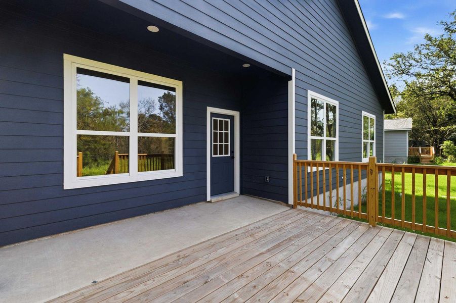 A well-maintained wooden deck extends from a contemporary dark-paneled home, offering serene views of the surrounding greenery. A well-maintained wooden deck extends from a contemporary dark-paneled home, offering serene views of the surrounding greenery.