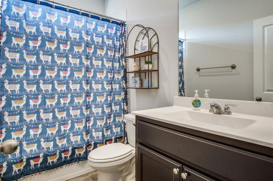 Bathroom featuring a shower with shower curtain, toilet, and vanity