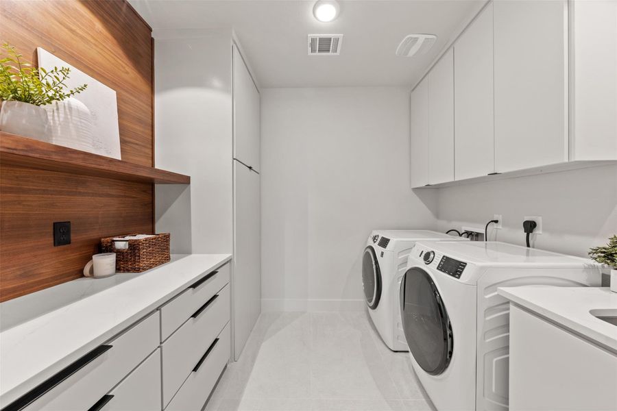 Washroom with cabinet space, independent washer and dryer, and light tile patterned floors