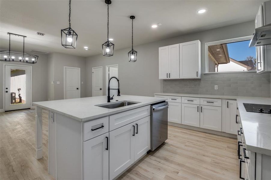 Kitchen with an island with sink, white cabinets, light stone counters, and recessed lighting Kitchen with an island with sink, white cabinets, light stone counters, and recessed lighting