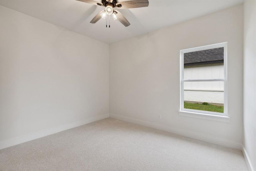 Carpeted spare room with baseboards and a ceiling fan