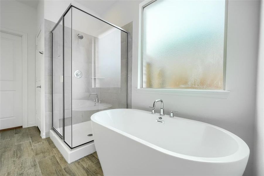 Full bath with a freestanding bath, a shower stall, and wood finish floors Full bath with a freestanding bath, a shower stall, and wood finish floors