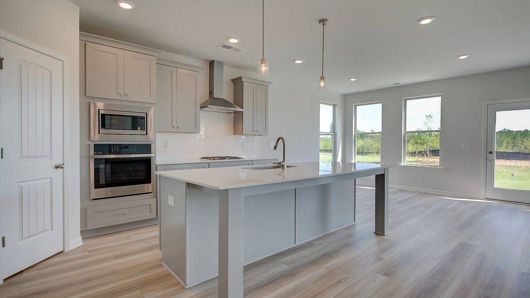 Open kitchen with large island, corner pantry, and stainless steel appliances in the Clarity at Brighton in Locust Grove, GA.