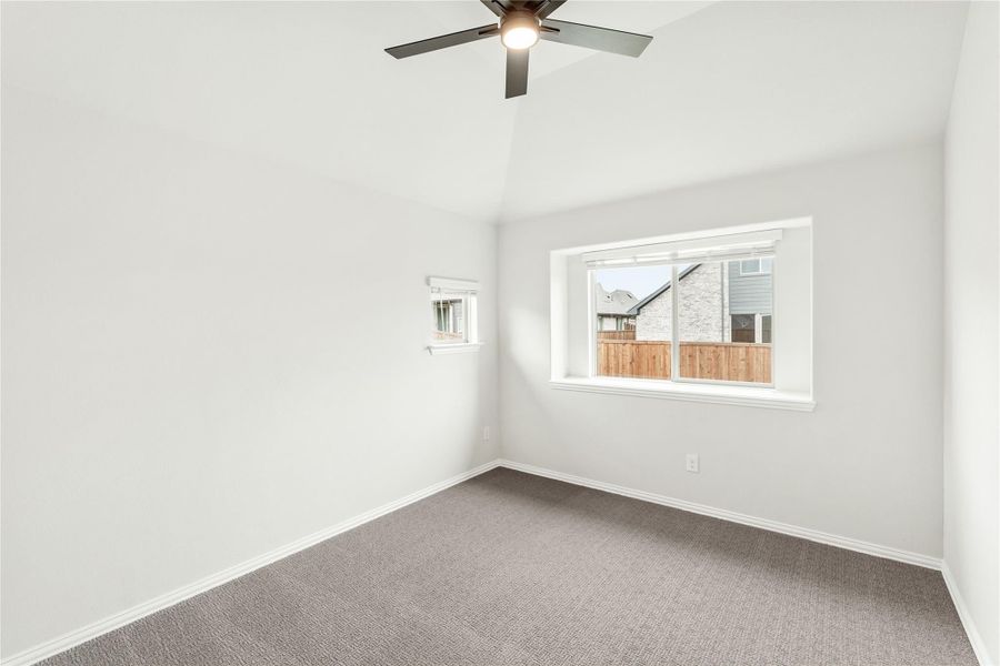 Empty bedroom with gray carpet, vaulted ceiling, ceiling fan, and two windows Empty bedroom with gray carpet, vaulted ceiling, ceiling fan, and two windows