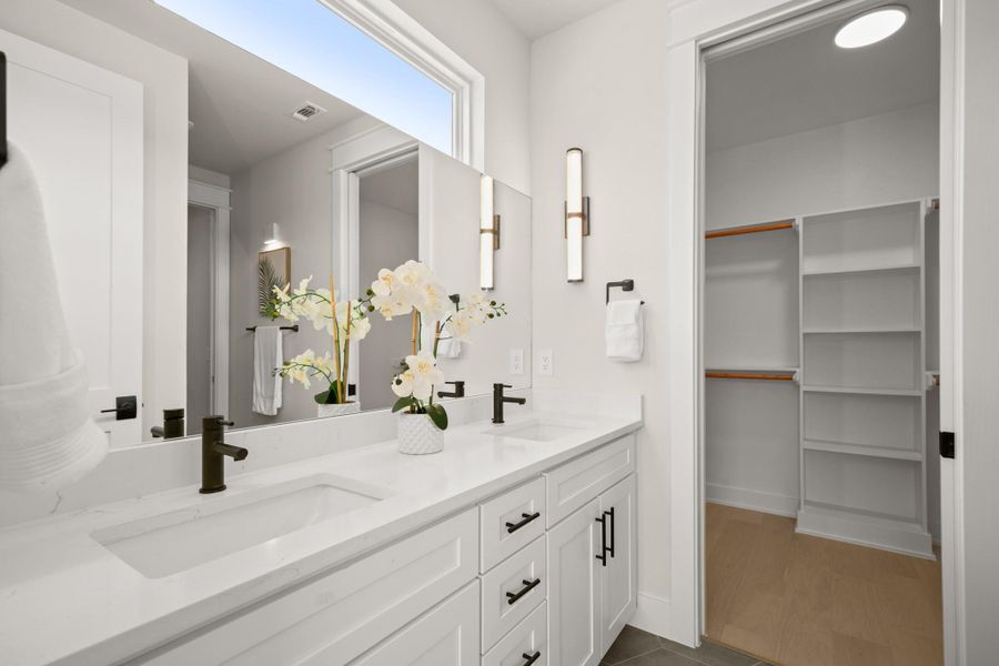 Bathroom featuring double vanity, dark tile patterned floors, and a spacious closet
