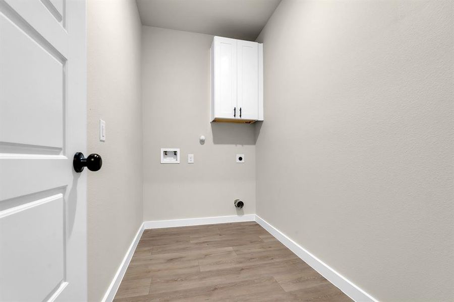 Clothes washing area featuring hookup for a washing machine, cabinets, gas dryer hookup, light hardwood / wood-style floors, and hookup for an electric dryer