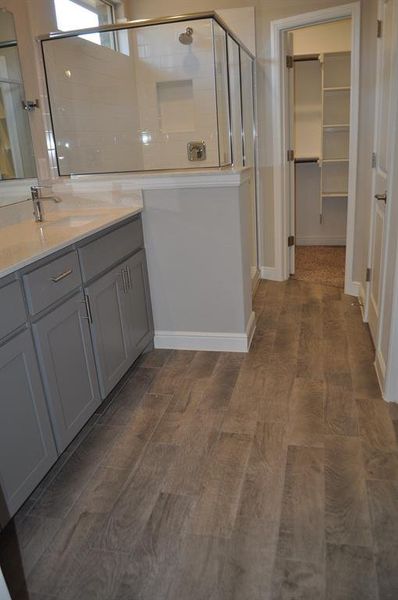 Bathroom featuring vanity, hardwood / wood-style floors, and a shower with door