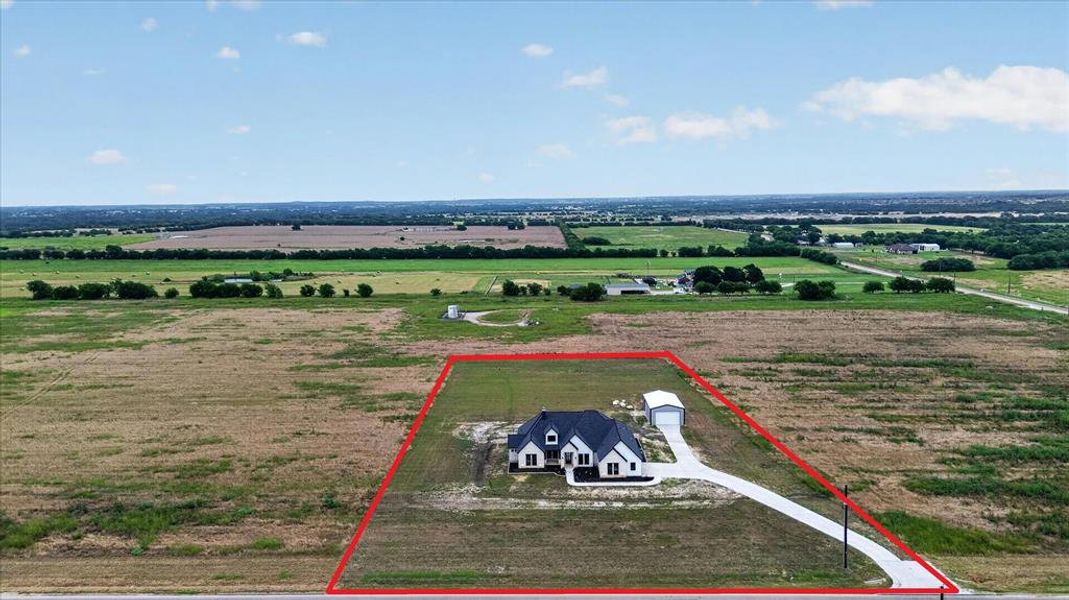 Aerial property overview highlighting a single-story residence with a dark gable roof and light-colored siding