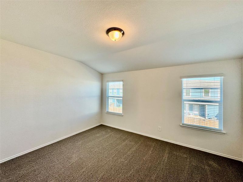Unfurnished room featuring lofted ceiling, a textured ceiling, and dark colored carpet