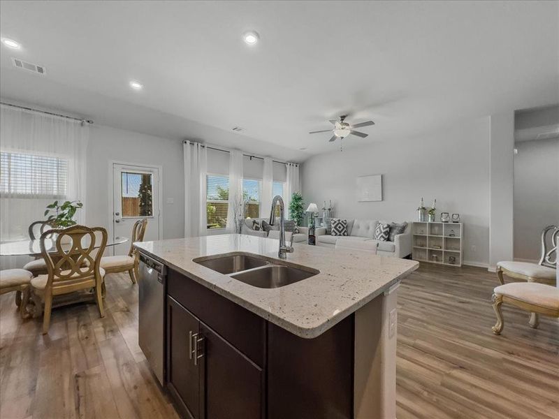 Kitchen with sink, dark brown cabinets, dishwasher, ceiling fan, and wood-type flooring