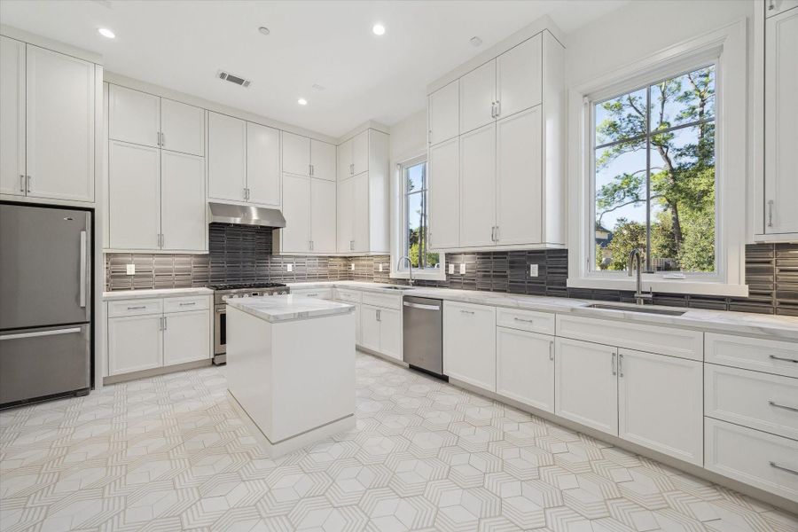 Cater's kitchen offers a full secondary prep space featuring a gas range and oven, refrigerator, dishwasher and double sinks with ample counter space and center island.