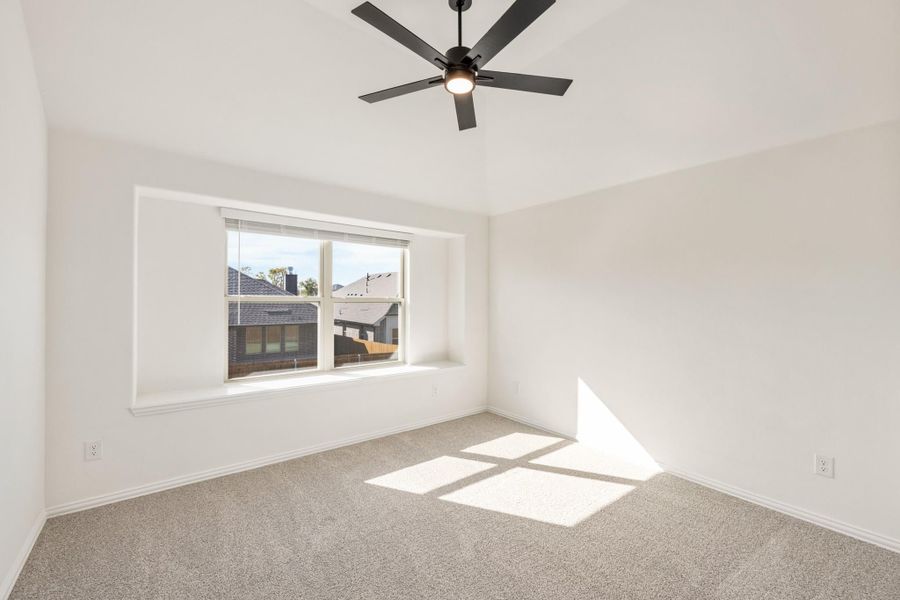 Empty bedroom with carpet flooring, black ceiling fan, and a window with natural light