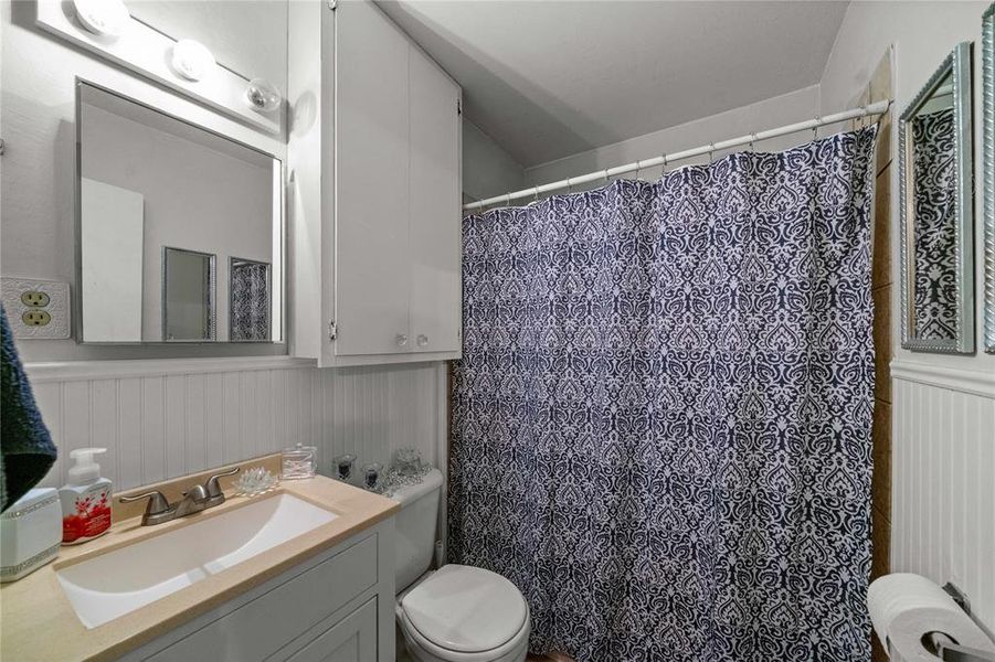 Bathroom with vanity, a shower with curtain, and wainscoting