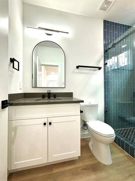 This photo showcases a magnificent contemporary bathroom accentuated by sleek lighting fixtures and black bathroom accessories.  The well-lit space serves the spacious secondary bedroom located on the first floor.