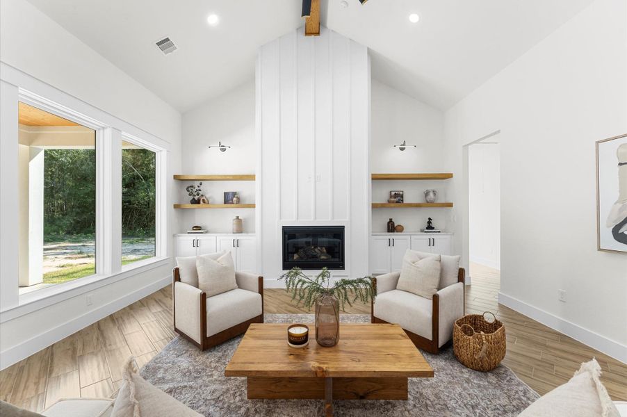 Grand living area with cathedral ceiling, cozy chimney, large windows for natural light, and open flow to the kitchen and dining—perfect for entertaining. Grand living area with cathedral ceiling, cozy chimney, large windows for natural light, and open flow to the kitchen and dining—perfect for entertaining.