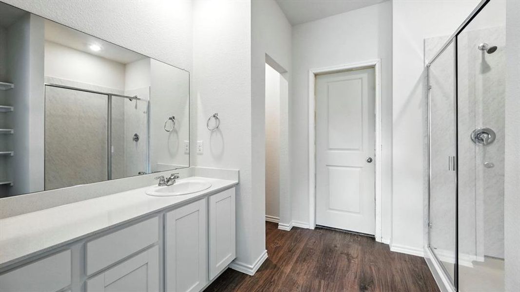 Bathroom featuring a vanity with an integrated sink, white cabinetry, and a large mirror