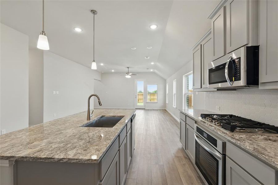 Kitchen with appliances with stainless steel finishes, gray cabinetry, a sink, lofted ceiling, and light wood-style flooring Kitchen with appliances with stainless steel finishes, gray cabinetry, a sink, lofted ceiling, and light wood-style flooring