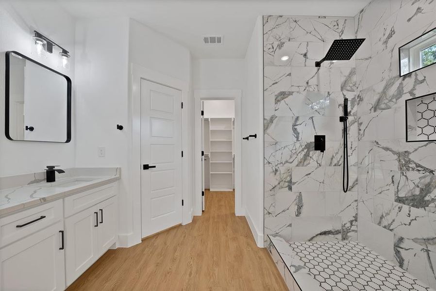 Full bathroom with a marble finish shower, vanity, a walk in closet, and light wood-type flooring