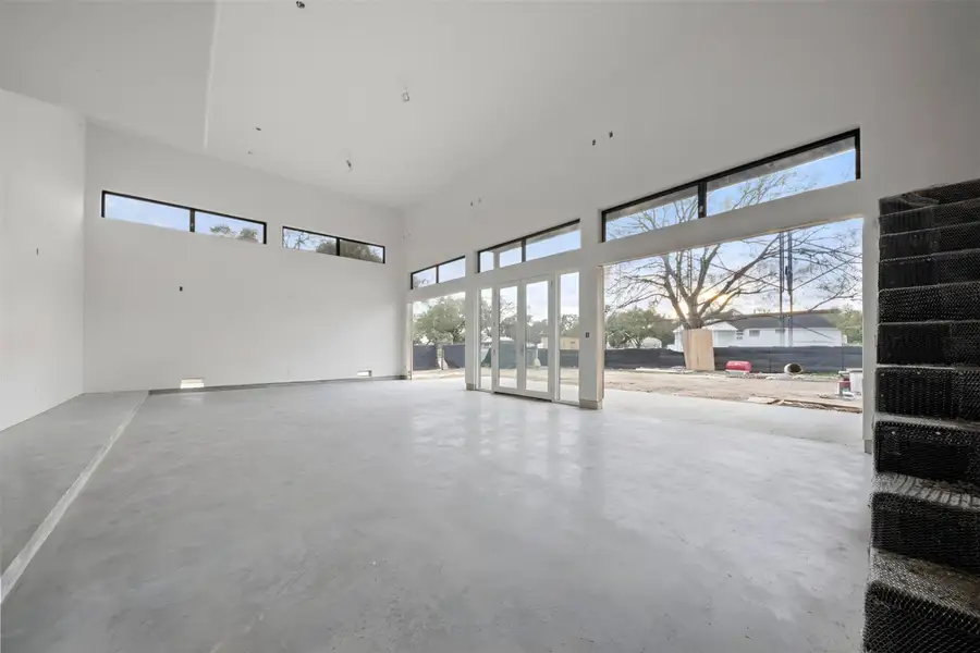 Three car garage with 20-foot ceiling clearance and full-height glass-panel garage doors. EV charging ready.