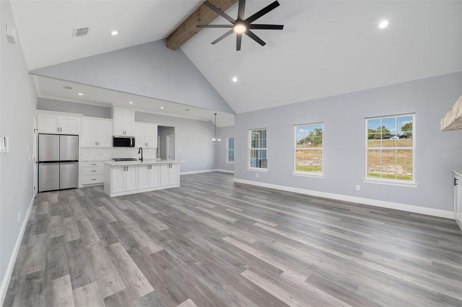 Unfurnished living room featuring beamed ceiling, high vaulted ceiling, light wood finished floors, recessed lighting, and ceiling fan Unfurnished living room featuring beamed ceiling, high vaulted ceiling, light wood finished floors, recessed lighting, and ceiling fan