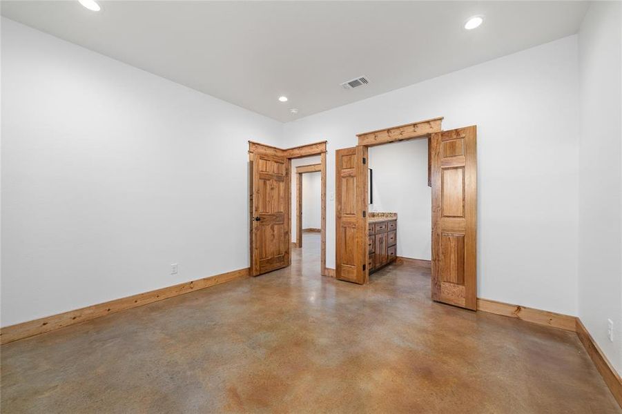 Unfurnished bedroom featuring recessed lighting, concrete floors, baseboards, and visible vents Unfurnished bedroom featuring recessed lighting, concrete floors, baseboards, and visible vents