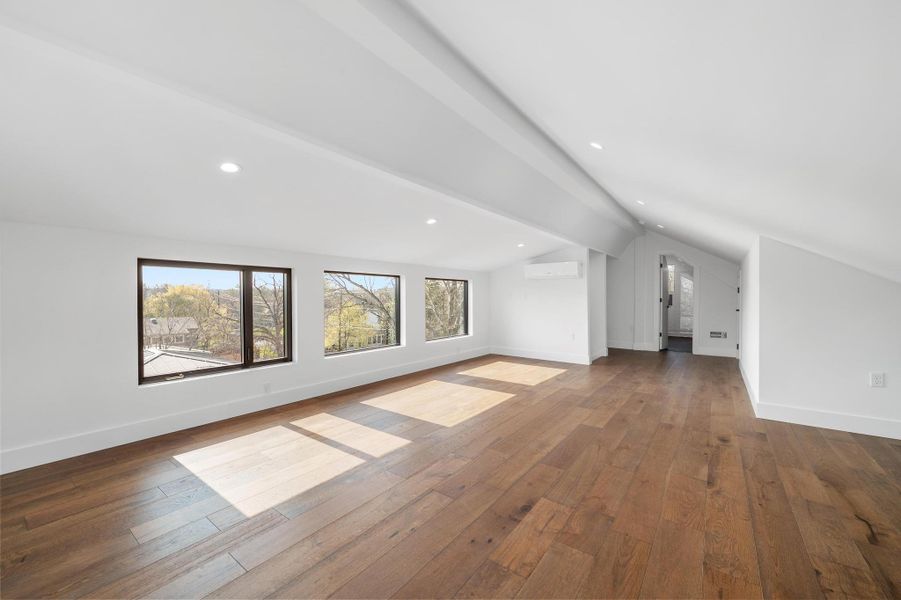 Bonus room featuring lofted ceiling with beams, baseboards, dark wood-style floors, and a wall mounted AC