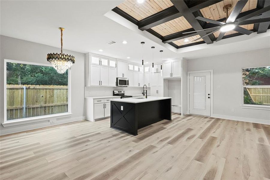 Kitchen with appliances with stainless steel finishes, a kitchen island with sink, a healthy amount of sunlight, white cabinetry, and hanging light fixtures