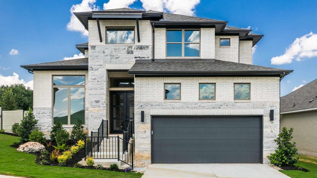 View of front of property with stone siding, concrete driveway, a garage, a shingled roof, and brick siding View of front of property with stone siding, concrete driveway, a garage, a shingled roof, and brick siding