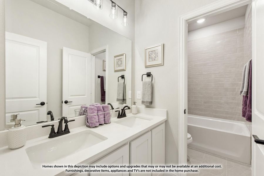 Bathroom with double sink vanity, white cabinets, large mirror, and tiled bathtub-shower combo