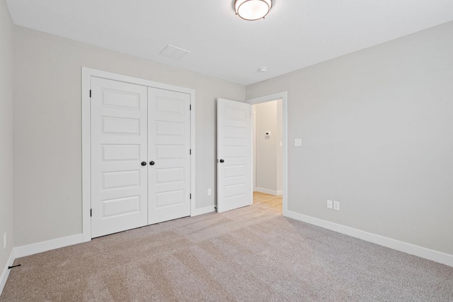 Spacious room featuring neutral carpeting, light gray walls, white trim, and a contemporary ceiling light fixture Spacious room featuring neutral carpeting, light gray walls, white trim, and a contemporary ceiling light fixture