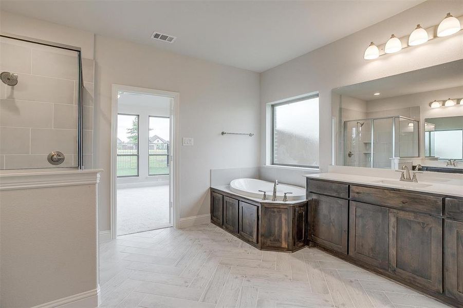 Bathroom with parquet floors, shower with separate bathtub, and vanity