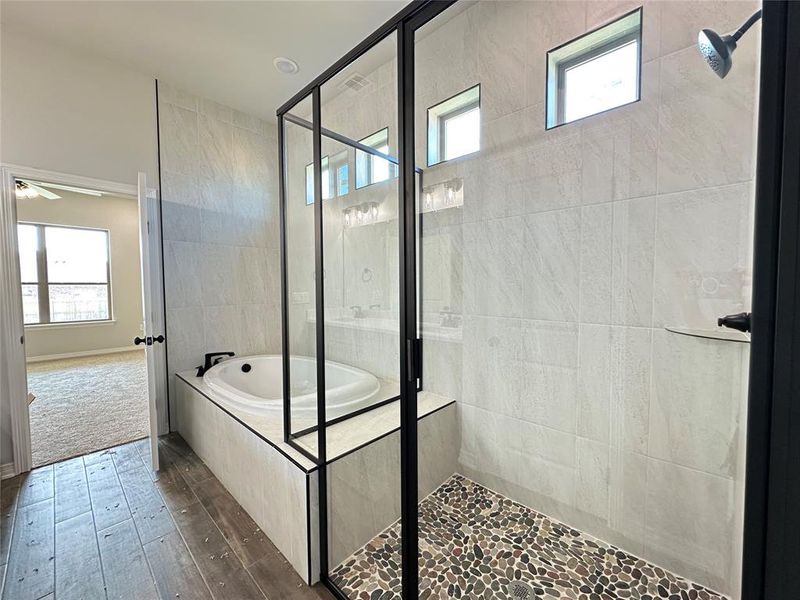 Full bath with a shower stall, healthy amount of natural light, a bath, and dark wood-style floors Full bath with a shower stall, healthy amount of natural light, a bath, and dark wood-style floors