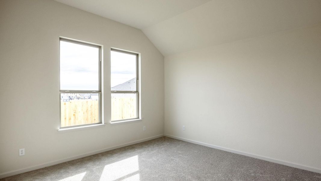 Additional living space with vaulted ceiling and carpet flooring