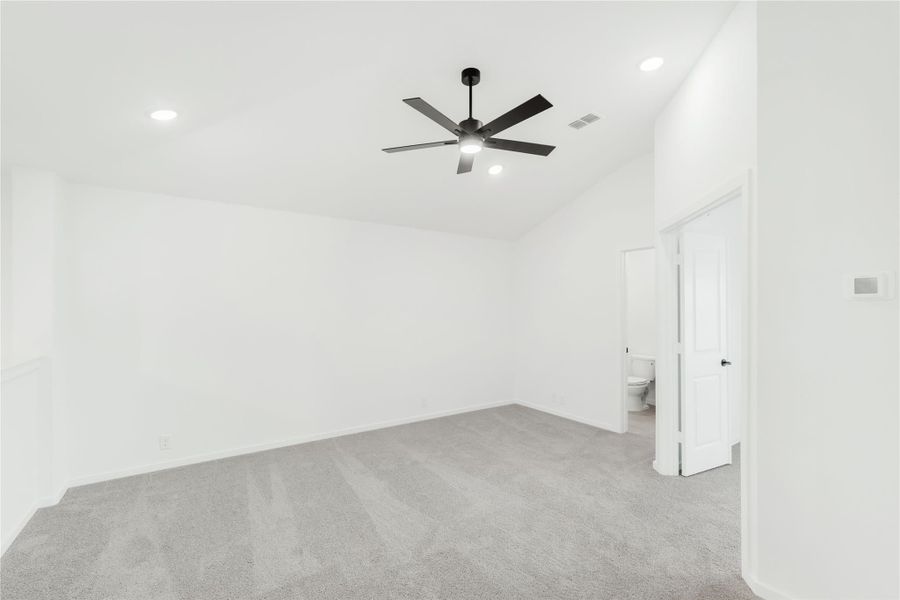 Empty bedroom with gray carpet, black ceiling fan, and open ensuite bathroom door Empty bedroom with gray carpet, black ceiling fan, and open ensuite bathroom door