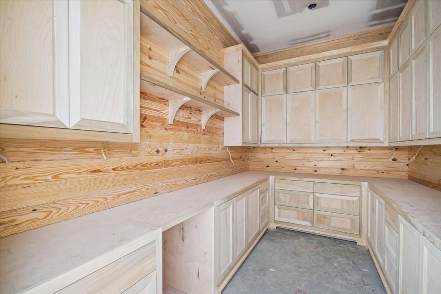 The walk-in pantry features extensive shelving, cabinetry, and countertop space designed to keep the kitchen organized and functional. Its layout supports both everyday storage and larger-scale entertaining needs. A well-appointed extension of the main kitchen that maximizes efficiency and workflow.