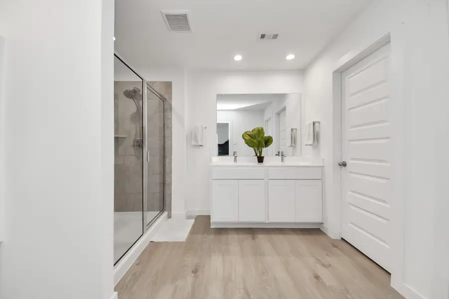 The primary bathroom features a stand alone glass shower perfectly situated to allow for extra space and a dual sink vanity.