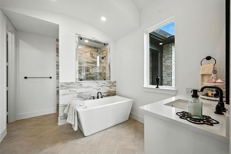 Full bathroom featuring vanity, a freestanding bath, a walk in shower, recessed lighting, and lofted ceiling