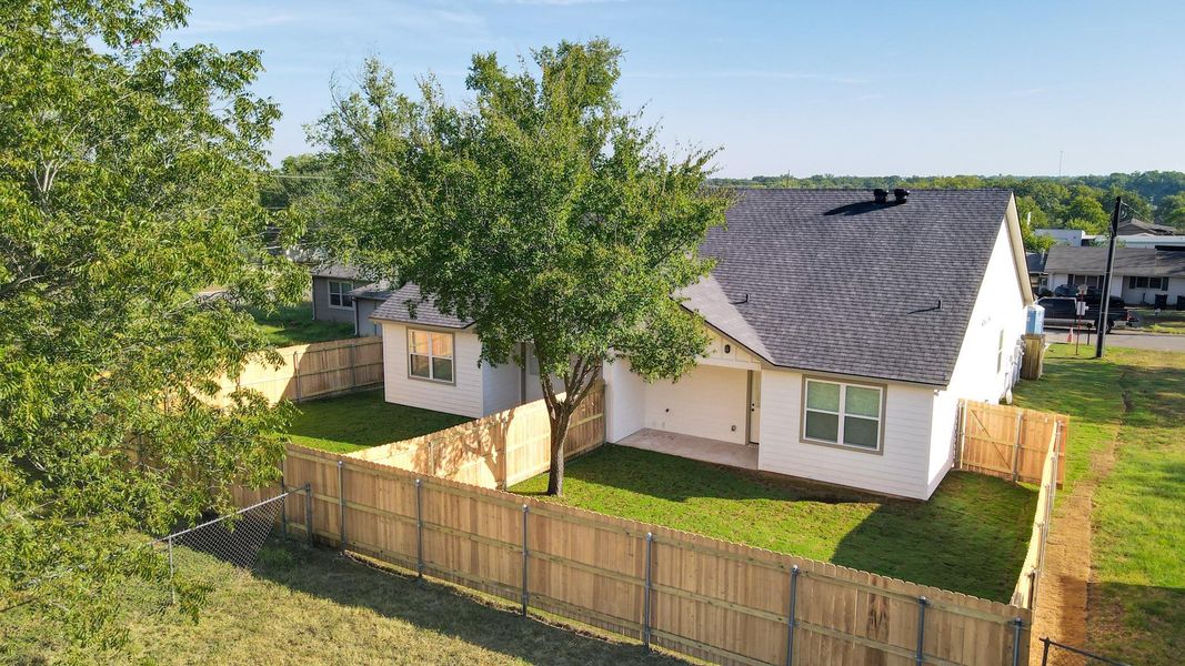 Rear view of house featuring a shingled roof and a fenced backyard