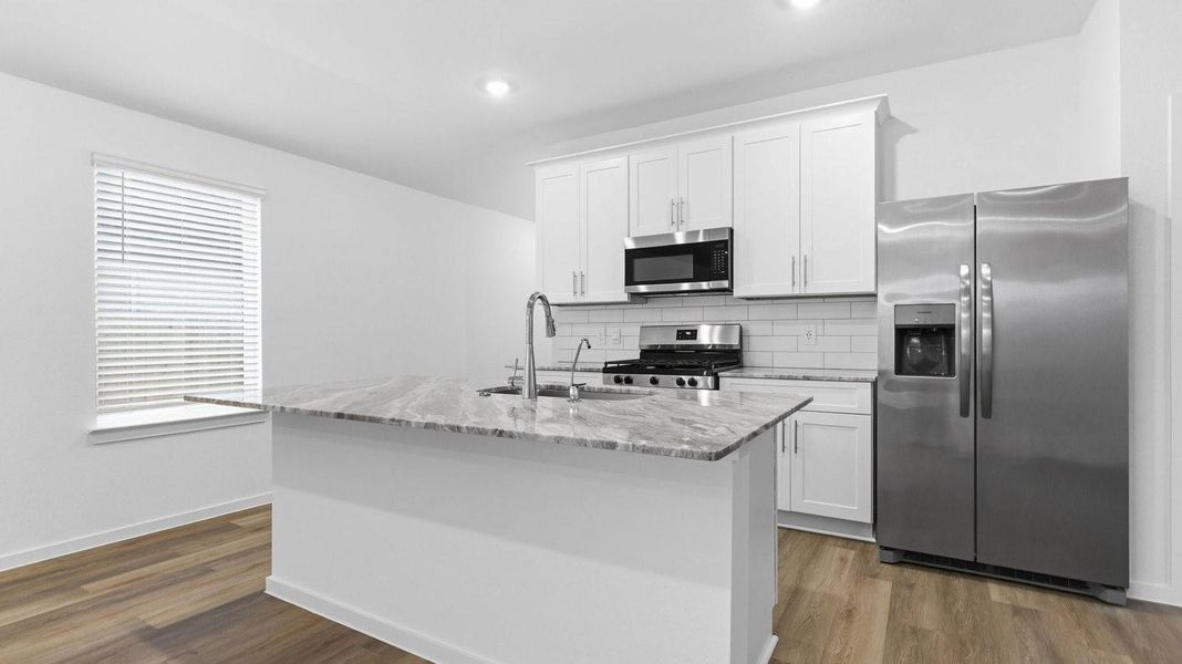 An open concept kitchen with an island with bar seating and access to the living and dining areas.