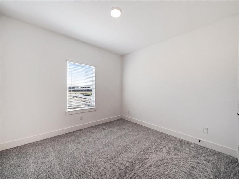 Carpeted spare room featuring baseboards