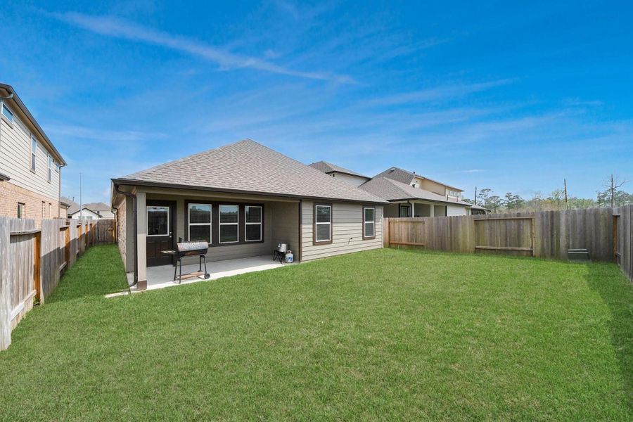 Expansive backyard with a large grassy lawn and full privacy fence, offering plenty of space for outdoor activities, pets, gardening, or future additions like a playset or outdoor seating area.